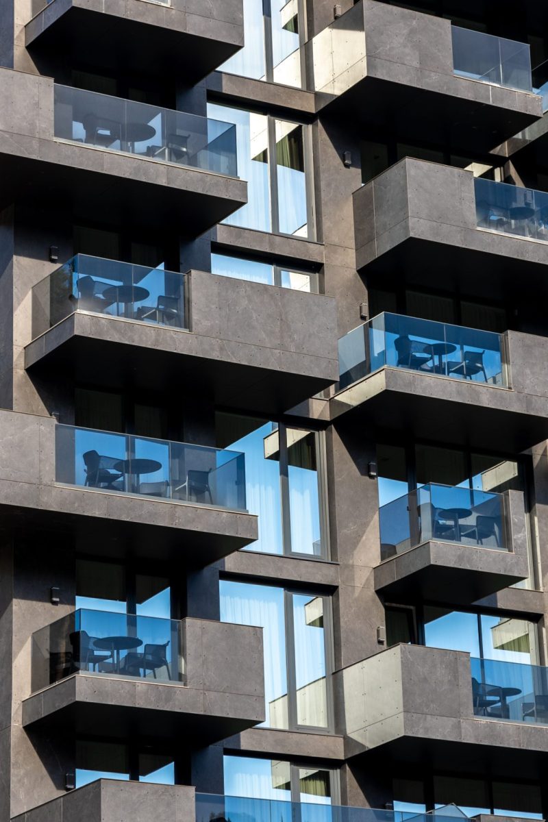Close-up of a modern building facade with concrete balconies and blue glass, creating rhythm, symmetry, and urban aesthetics.