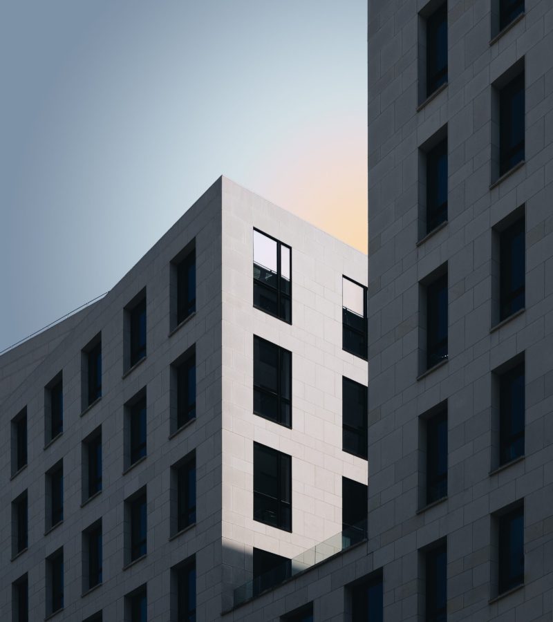 A vertical shot of a grey concrete building under the blue sky