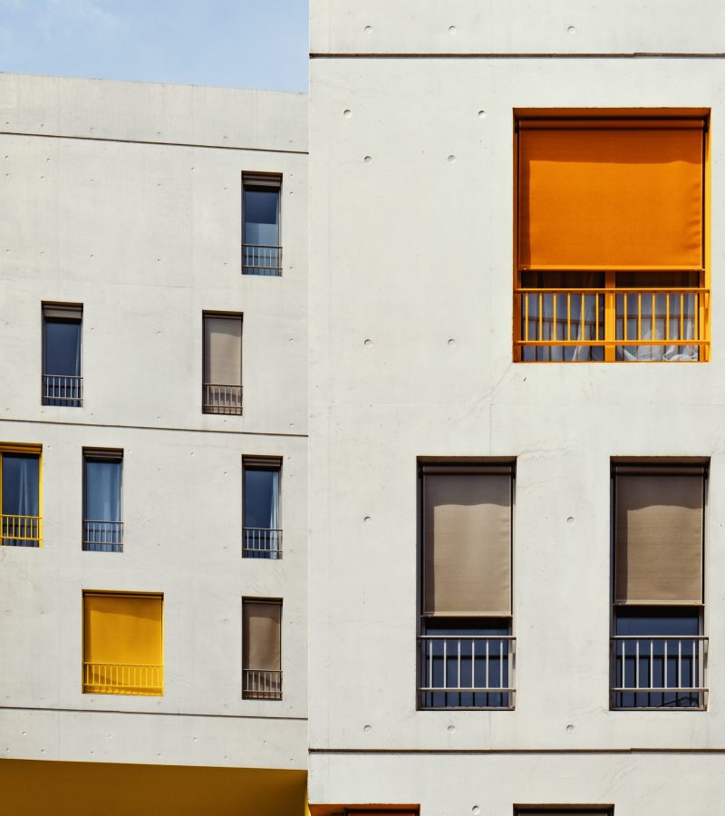 A vertical shot of white buildings with colorful curtains in the windows