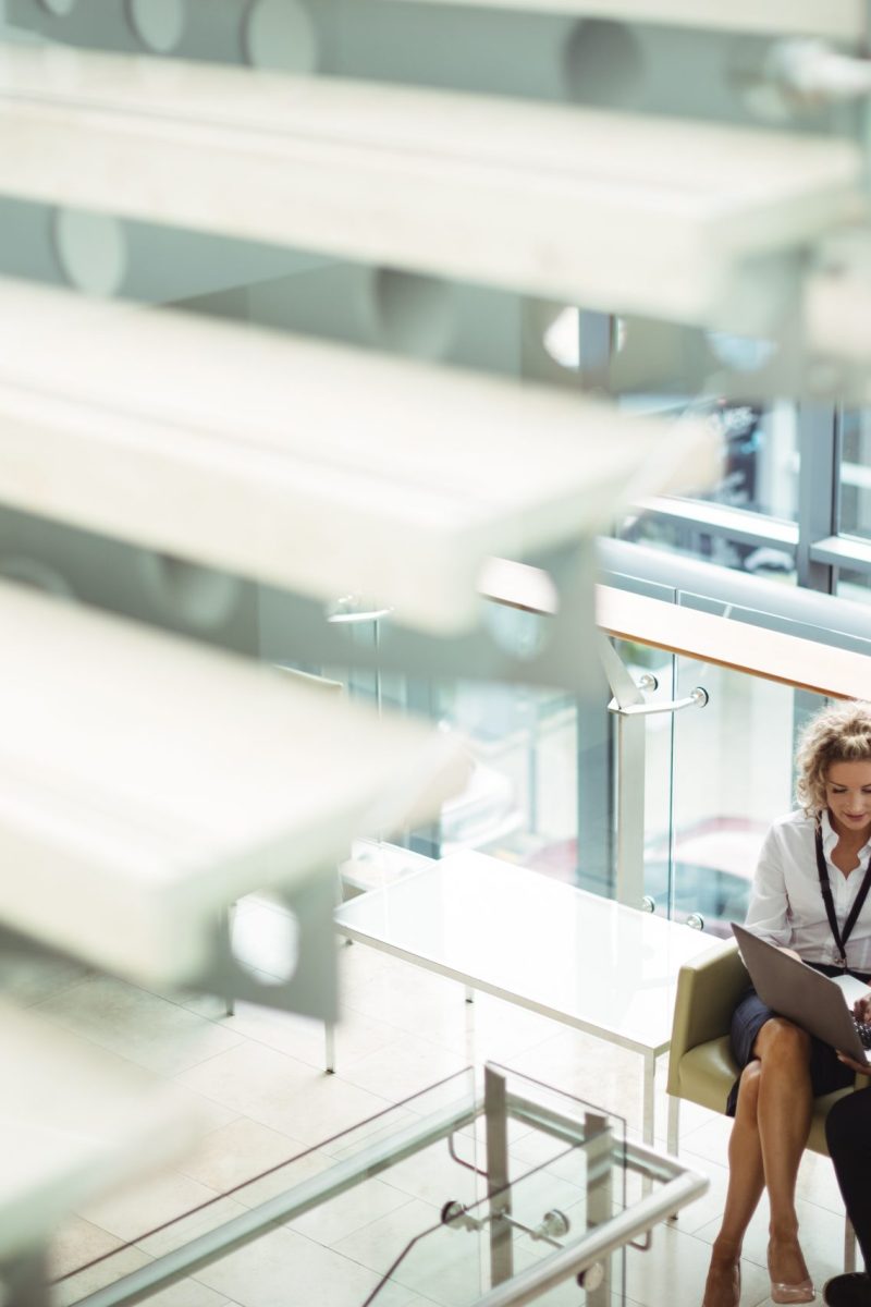 Business executives discussing over laptop at office corridor