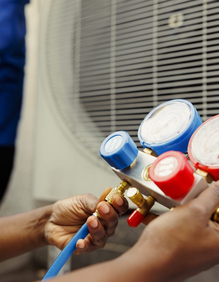 Close up of competent mechanic holding manometers used for checking hvac system refrigerant. Expert repairman using manifold indicators to check high or low freon levels of air conditioner tank