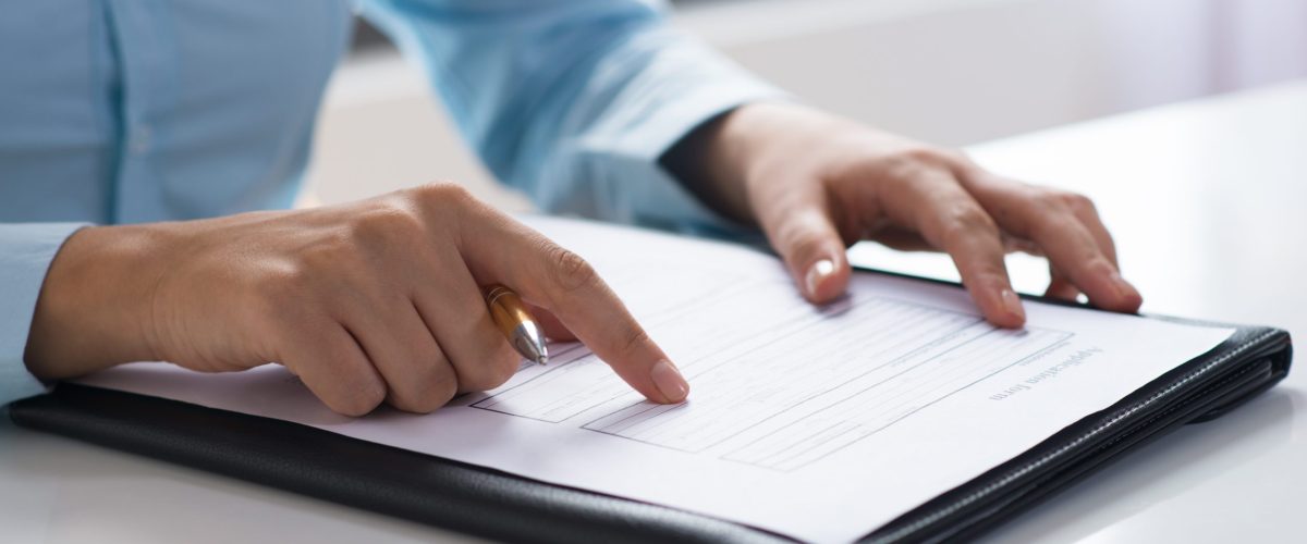 Closeup of person reading and studying document. Entrepreneur sitting at desk. Paperwork concept. Cropped view.